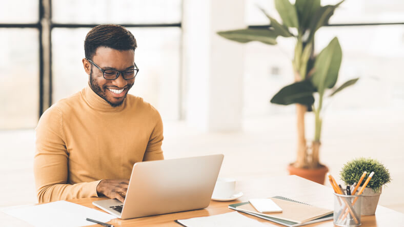 A freelancer who has completed an accounting diploma smiling at his desk