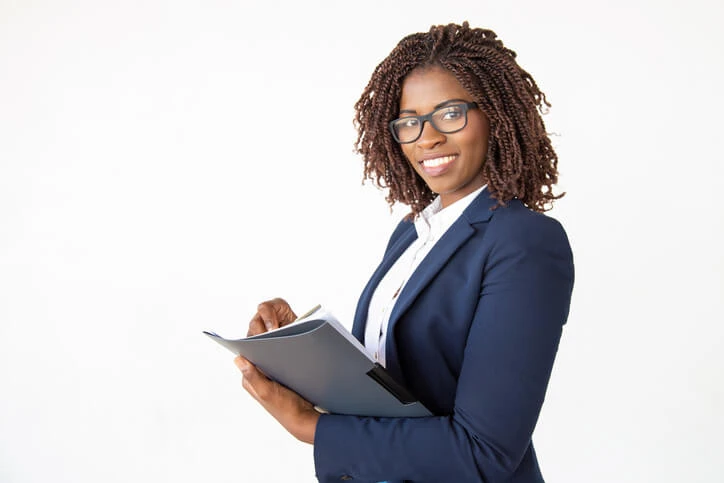 A smiling female legal assistant holding a notepad after legal assistant training.