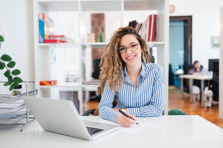 Administrative assistant diploma graduate sitting at a desk.