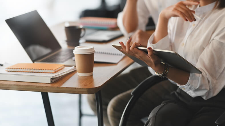 administrative assistant diploma graduate using a tablet while sitting at a desk