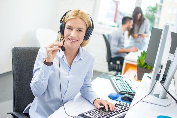 A female administrative assistant communicating with customers in an office setting after completing her administrative assistant diploma program