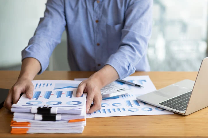 An accountant with a stack of papers with graphs on them.