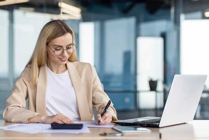 A smiling female accounting clerk writing a report in an office after accounting training.