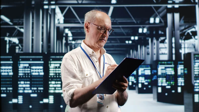 A network administrator taking notes in a server room.