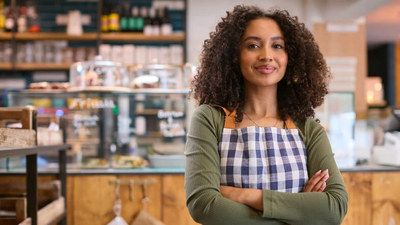 A friendly female sales assistant working in a food shop after completing her administrative assistant training.