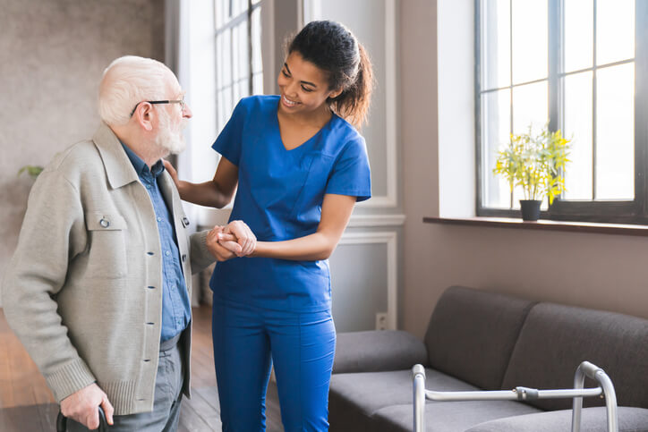 A female home support worker communicating with an elderly male patient at home