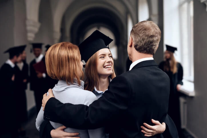 A happy female career college graduate with parents.