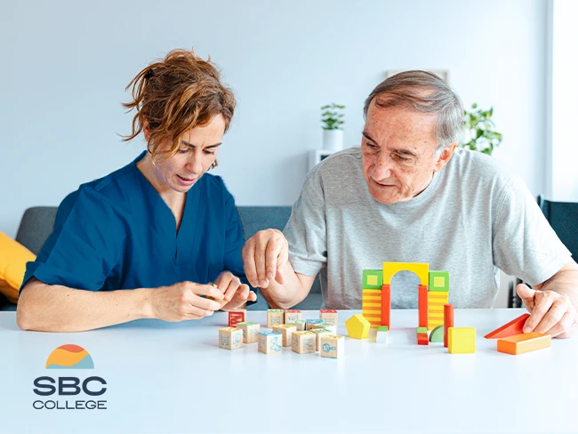 A continuing care assistant (CCA) engaging with a senior while playing a block game.