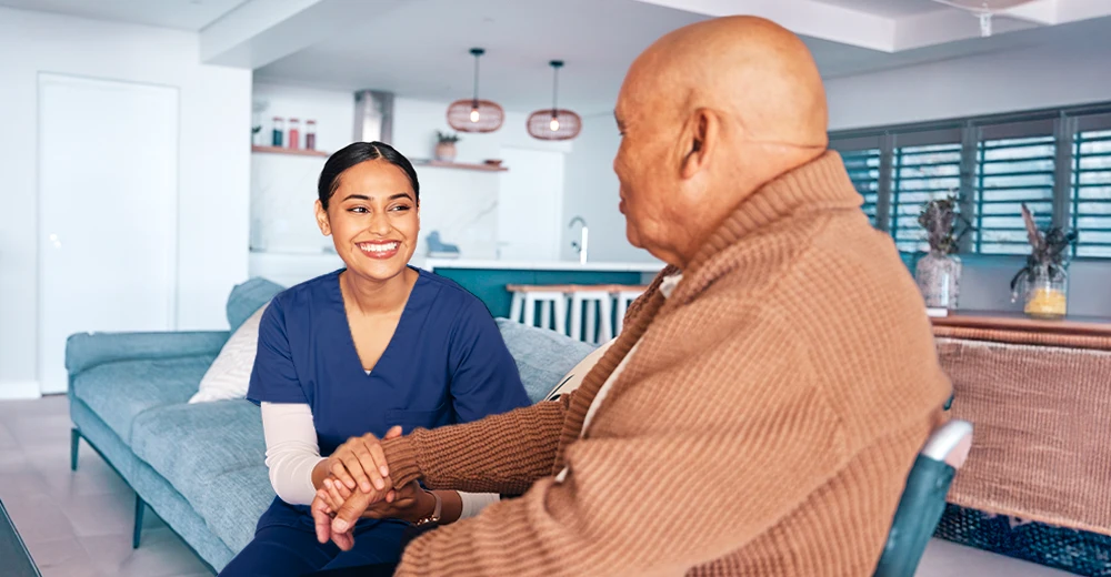 Personal care aide talking with a wheelchair-bound patient at home, building trust and connection.