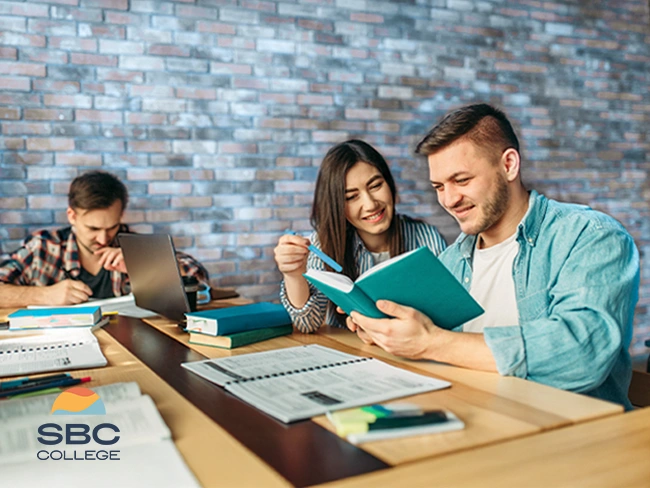 Two college students collaborating on a group project, showing teamwork, communication, & collaboration skills valued in job applications & student resumes.