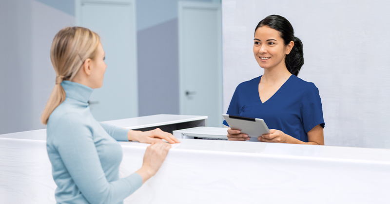 A medical office administrator checking in patients at a healthcare reception desk.