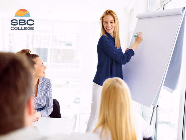 A young woman smiles while working in a business office, an example of developing a professional career with a Business Administration Management Diploma