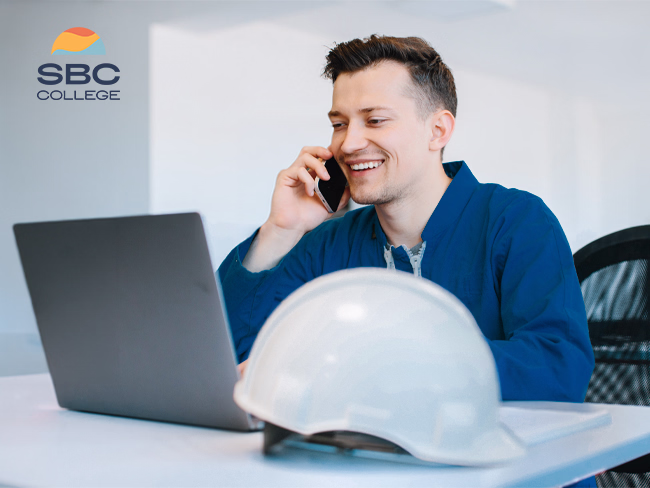 A male Mining Industry Business Specialist working on a computer while speaking on the phone in an office setting.